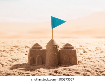 Sand Castle With A Flag On The Sea Shore.