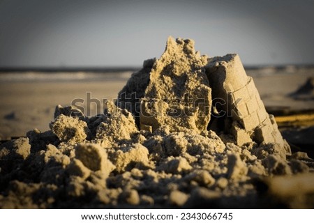 A sand castle on a beach that has collapsed