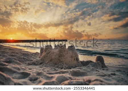 Sand castle on empty beach. Background with empty coastline at sunset.