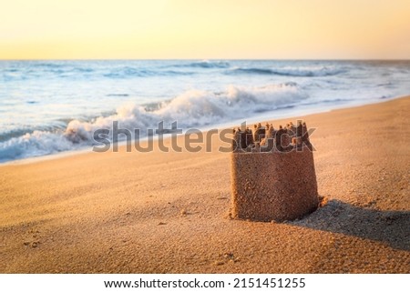 Sand castle on sandy beach in sea shore at sunset time , summer holiday vacation at tropical island.