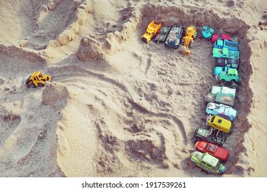 Sand Castle Top View On Sea Beach With Kids Toys. Sand Castle Or Fort With Many Colorful Plastic Car On Summer Sea Coast Overhead View. Abstract Background.