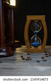 Sand Clock And Scattered Grains Of Roasted Coffee On A Vintage Rough Wooden Background. Sandglass, Hourglass Or Egg Timer On Wooden. Antique Style Wooden Background.