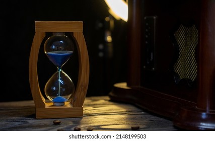 Sand Clock And Scattered Grains Of Roasted Coffee On A Vintage Rough Wooden Background. Sandglass, Hourglass Or Egg Timer On Wooden. Antique Style Wooden Background.