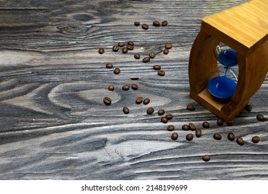 Sand Clock And Scattered Grains Of Roasted Coffee On A Vintage Rough Wooden Background. Sandglass, Hourglass Or Egg Timer On Wooden. Antique Style Wooden Background.