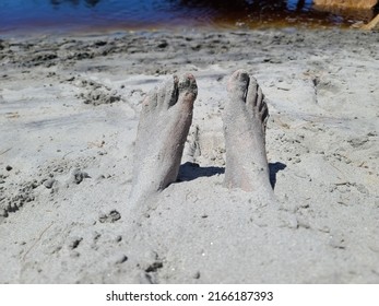 Sand Covered Toes And Feet In The Sand At A Beach. The Man's Feet Are Sitting At The Bottom Of A Whole In The Sand.