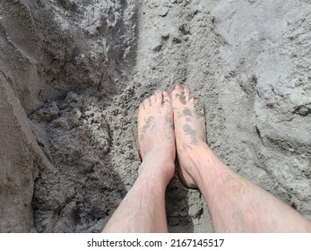 Sand Covered Toes And Feet In The Sand At A Beach. The Man's Feet Are Sitting At The Bottom Of A Whole In The Sand.