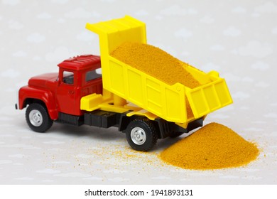 Sand Delivery By Dump Truck. Toy Truck Pours The Sand On The Ground