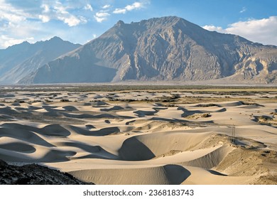 Sand dune pattern with mountain and blue clouds sky background in Nubra valley in Diskit, India.