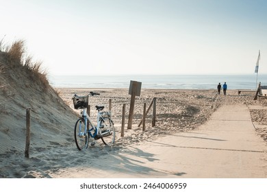 Sand dunes on the sea coast in Noordwijk, Netherlands. Two men walking with dog on the beach. Beautiful summer seascape at sunset - Powered by Shutterstock