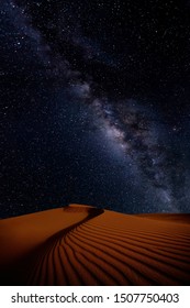 Sand Dunes Ripples By The Wind Under The Starry Night Sky. Milky Way Galaxy Above Desert