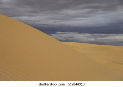 Sand Dunes With Storm Clouds At Sunset. Nature And Travel. Mongolia, Gobi Desert