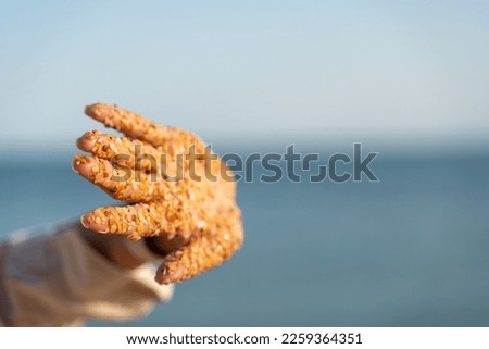 Sand hand sea. Small pieces of shells sand stuck to the palms of a woman against the backdrop of the sea and blue sky.