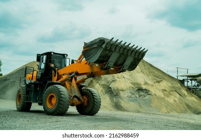 Sand loaders are shoveling rocks into dump trucks.