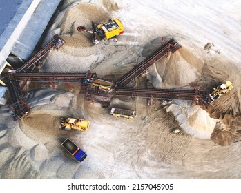 Sand Making Plant and Belt conveyor in mining quarry. Mining excavator loading sand in haul truck in opencast.  Sand crushing and bulk materials for construction industry. Open-pit mining.