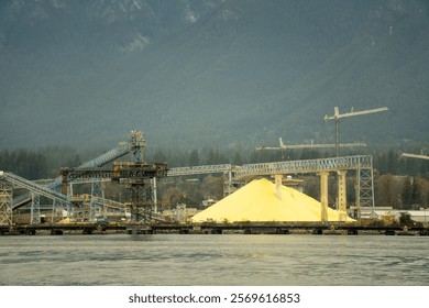 a sand mining and processing plant built on the river, with cranes and chutes to transfer the sand to cargo ships