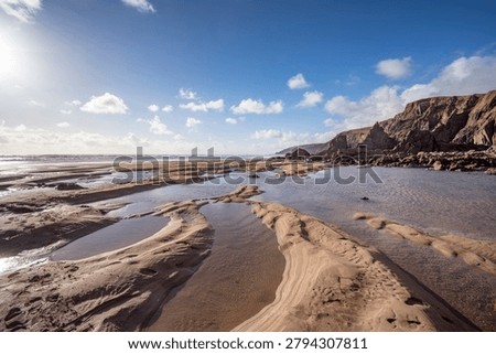 Sand pools shape by the outgoing tide in Cornwall as the sun is about to set