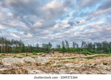 Sand Quarry On The Edge Of The Forest, Soil Erosion. Sky With Clouds Over Them In The Sunset.