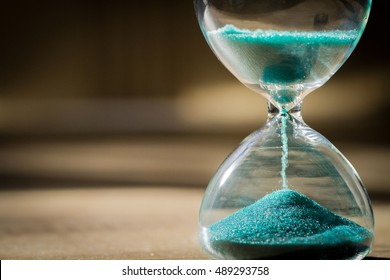 Sand Running Through The Bulbs Of An Hourglass Measuring The Passing Time In A Countdown To A Deadline, On A Dark Background With Copy Space.