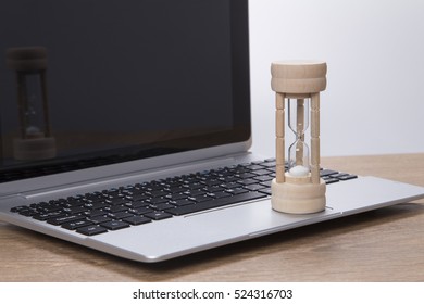 Sand Running Through An Egg Timer On A Laptop Computer Measuring Passing Time As It Counts Down To A Deadline In The Office Or Conceptual Of Pressure And Stress