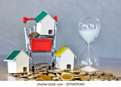 Sand Running Through The Shape Of Hour Glass, Miniature House And Shopping Cart Models With Coin Spilling On Table. Countdown Timer For Business Deadline Concept.