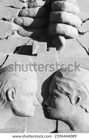 A sand sculpture in black and white in the form of the faces of two people facing each other.