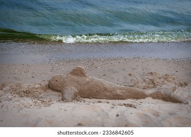 A sand sculpture of a dolphin, left by visitors to a sand sculpting festival, begins to wash away on shores of Lake Michigan at Manitowoc, Wisconsin. - Powered by Shutterstock