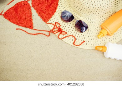 Sand Texture (background) With Hat, Swimsuit, Sunscreen (suncream), Sunglasses On The Beach. The Sun Drawing In The Sand. The Empty Pattern For Message. Summer Vacations Concept. Copy Space.