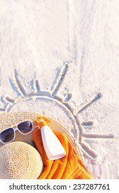 Sand Texture (background) With Hat, Towel, Sunscreen (suntan Lotion, Suncream), Sunglasses On The A Beach. The Sun Drawing In The Sand. The Empty Pattern For Message. Summer Vacations. Copy Space. 