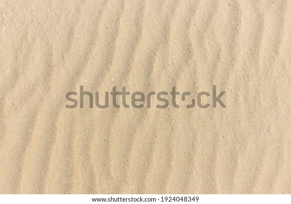 Sand texture. Sandy beach\
for background. Top view. Natural sand stone texture background.\
sand on the beach as background. Wavy sand background for summer\
designs.