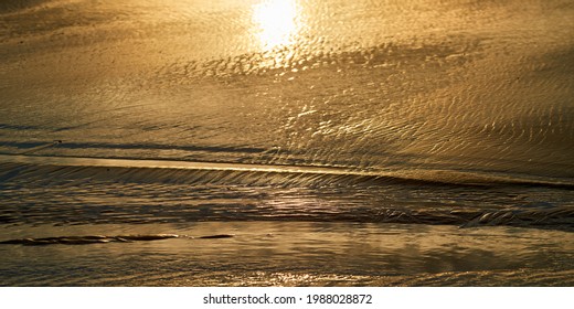 Sand texture with sun reflection at low tide on the beach in Barview Jetty Park at sunset time.