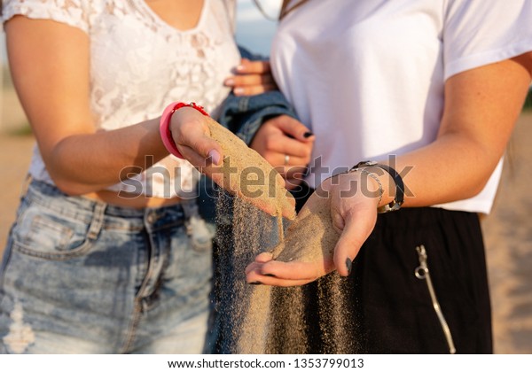Sand as the time slips through your fingers. Girls\
holding a sand sea background. concept of vacation in warmer\
climes, the trip to the\
sea