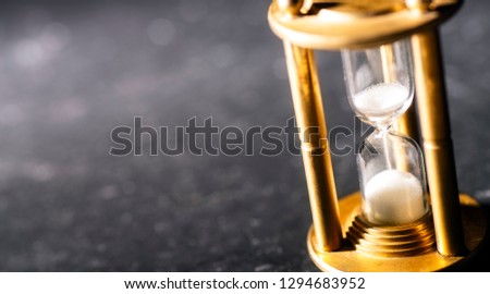 Sand trickles through an hourglass, symbolizing timekeeping.