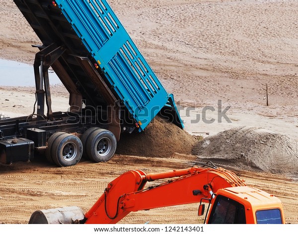 The sand truck is pouring sand
on the ground.for construction and build a road for landmark    
