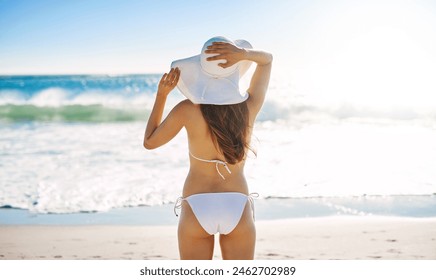 Sand, waves and back of woman by ocean for summer vacation, peace and adventure on holiday. Bikini, sun hat and person with sunshine at beach for tropical, island travel and tourism in Maldives - Powered by Shutterstock