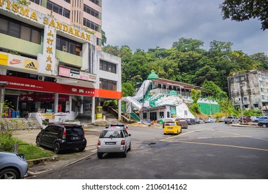 Sandakan, Malaysia - January 06, 2022: Cityscape of the in Borneo. Rundown houses and old Malaysian cars on the street. Second largest city of Sabah. Old mosque in the background. City view Sandakan