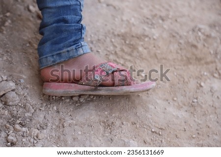 A sandal with pink straps and a little boy's foot detail.