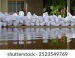 Sandbag for flood protection. A pile or wall of sandbags at the front entrance of a house, next to street, to keep flooding water out of the residence