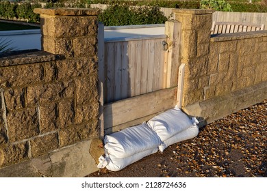 Sandbags Piled Against A Garden Gate Protecting A Seafront Property Against Flooding And A Tidal Storm Surge