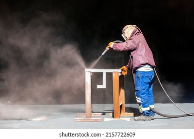 Sandblaster is sandblasting to steel material. Sand blasting is also known as abrasive blasting, which is a generic term for the process of smoothing, shaping and cleaning a hard surface by forcing. - Shutterstock ID 2157722609