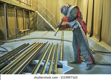 Sandblasting in chamber. Worker makes sand blast cleaning of metal detail