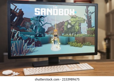 The Sandbox Game Metaverse Game On Computer Screen. Monitor, Keyboard And Airpods On Wooden Table. Selective Focus. Rio De Janeiro, RJ, Brazil. May 2022.