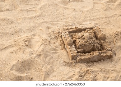 Sandcastle frames a small, rough figure. Soft sunlight glows on the beach's quiet scene. Fingers carved a playful, earthy form. Simple structure hints at childhood joy. Ideal for summer, vacation.
