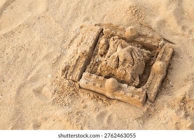 Sandcastle frames a small, rough figure. Soft sunlight glows on the beach's quiet scene. Fingers carved a playful, earthy form. Simple structure hints at childhood joy. Ideal for summer, vacation.