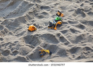 Sandcastle With Kids Toys. Sand Castle Or Fort With Many Colorful Plastic Car On Summer Sea Coast Overhead View. Abstract Background.