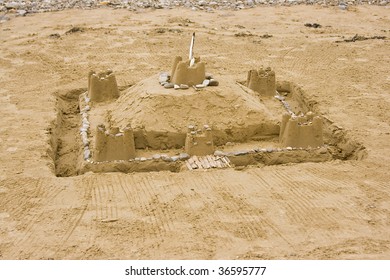 Sandcastle With A Moat And Feathers For Decoration