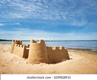 Sandcastle On The Sea In Summertime. Seashore On Beautiful Day. Sand On The Beach And Blue Water