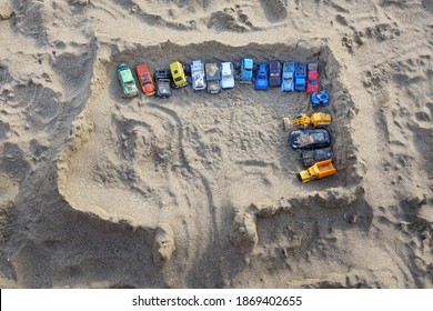 Sandcastle Top View On Sea Beach With Kids Toys. Sand Castle Or Fort With Many Colorful Plastic Car On Summer Sea Coast Overhead View. Abstract Background.