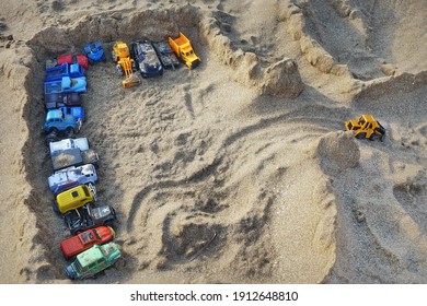 Sandcastle Top View On Sea Beach With Kids Toys. Sand Castle Or Fort With Many Colorful Plastic Car On Summer Sea Coast Overhead View. Abstract Background.