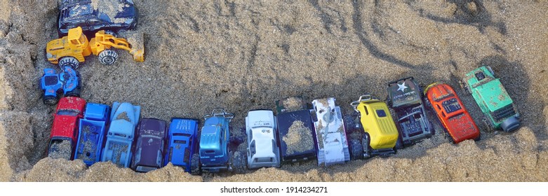 Sandcastle Top View On Sea Beach With Kids Toys. Sand Castle Or Fort With Many Colorful Plastic Car On Summer Sea Coast Overhead View. Abstract Background.