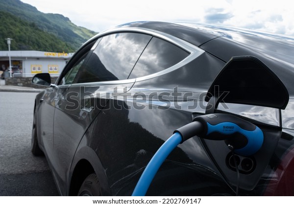 Sandeid, Norway - June
7, 2022: A static shot of a solid black Tesla Model 3 dual motor
charging at the Haugaland Kraft AC charging station in a rainy
spring day. Selective
focus.